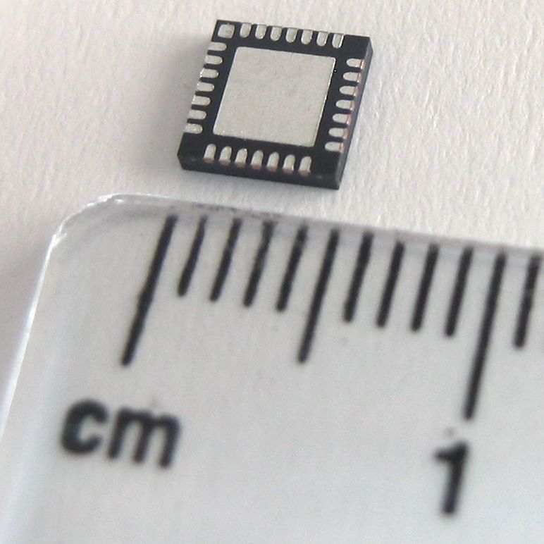 Thermal via array under a QFN IC package on PCB — multiple copper-filled vias conduct heat from the exposed pad down to the ground plane heatsink